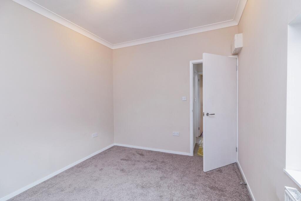 Bedroom painted off white with neutral carpet and white door