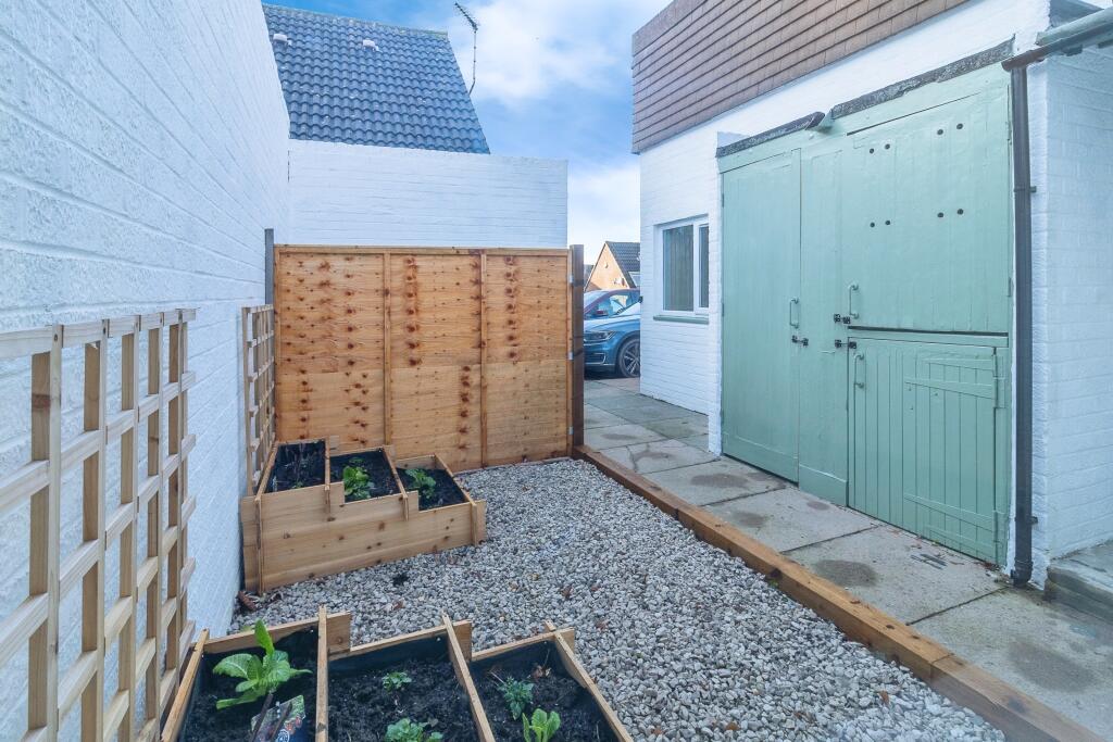 Front garden showing gravel area with fencing enclosing bins and outside storage cupboards.